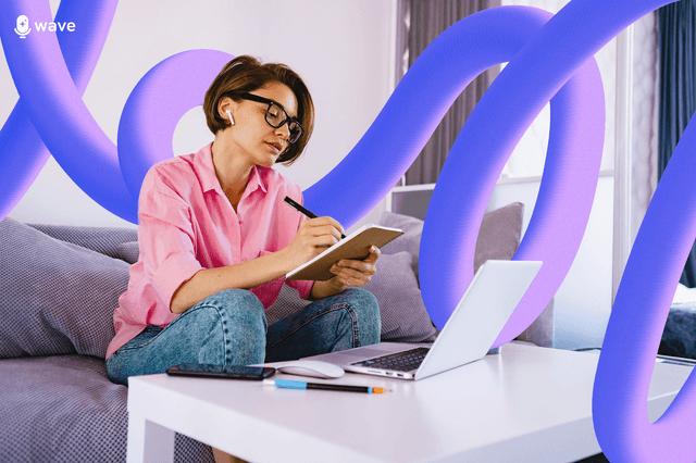 A woman taking notes on a notepad in front of a laptop
