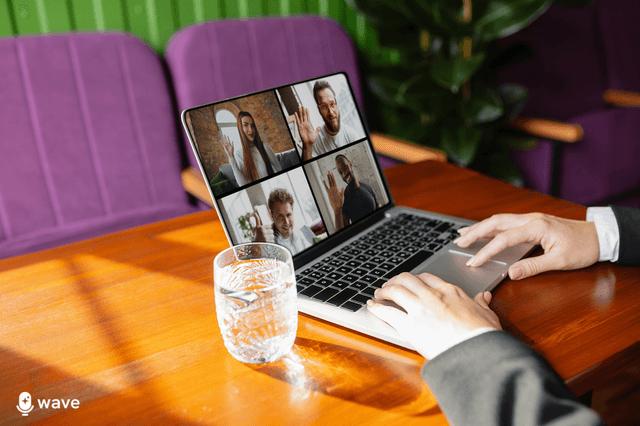 A laptop showing an online meeting, sitting on a modern deesk.