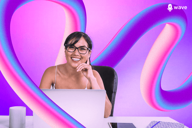 A you ng woman wearing glasses sitting behind a laptop.