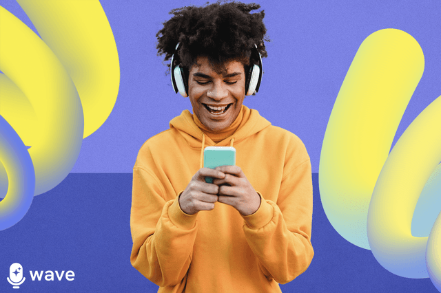 A man in a yellow hoodie wearing headphones smiling at a media device he's holding