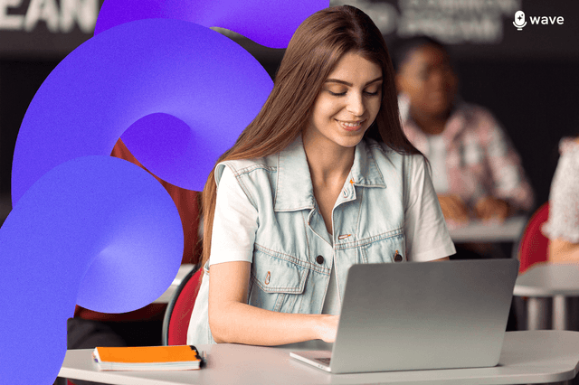 A woman taking notes in class on her laptop while smiling