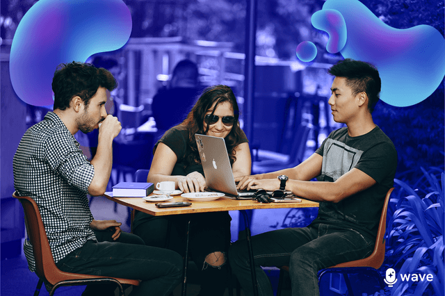 Three people working around a laptop in a coffee ship